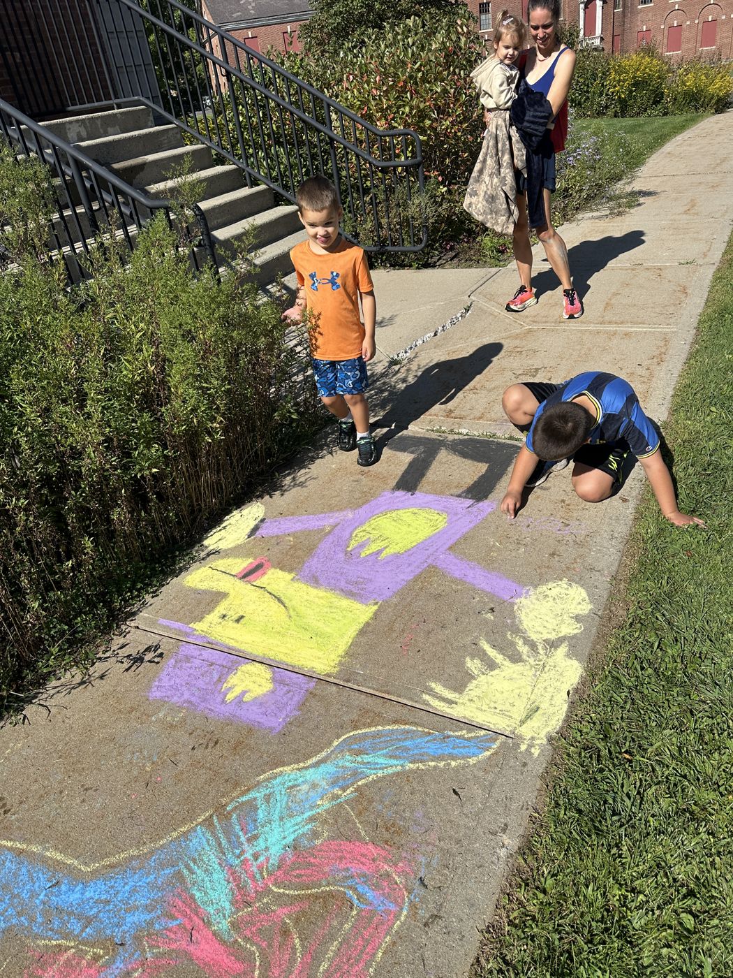 Young artists drawing along the sidewalk