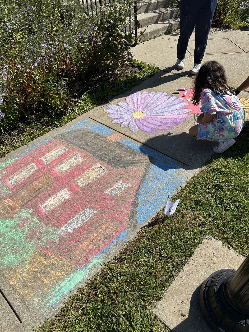 An artist drawing bold chalk flowers