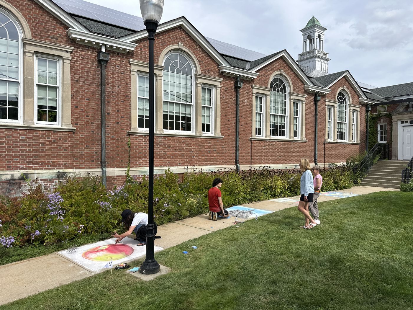 Artists working on the lawn in front of the brick campus buildings